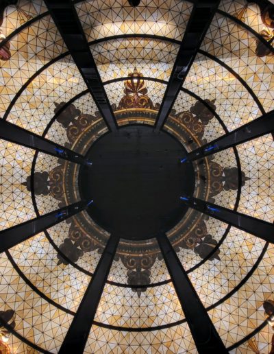 Within the Oklahoma Capitol Dome, a circular stained glass ceiling intertwines with a magnificent mirror, casting a kaleidoscope of vibrant hues and enchanting reflections. A masterpiece of elegance and grandeur.